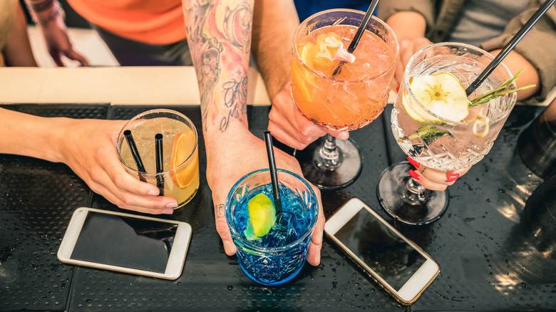 hands holding cocktails at bar