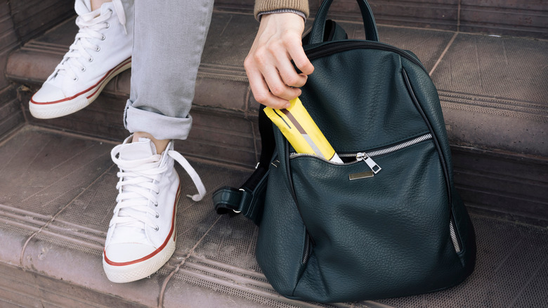 Woman pulling protein bar out of backpack