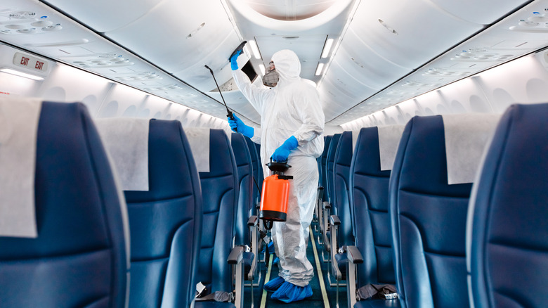 Protective-suited workers cleaning airplane