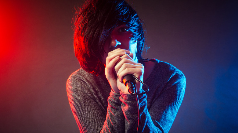A man with an emo haircut sings into a microphone