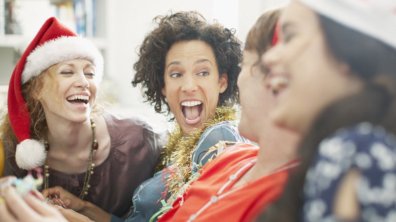 Women in Santa hats and Christmas clothes laughing