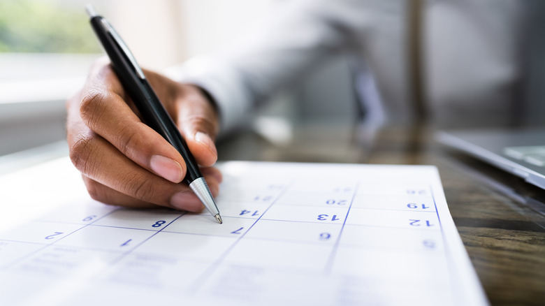 Person writing on calendar