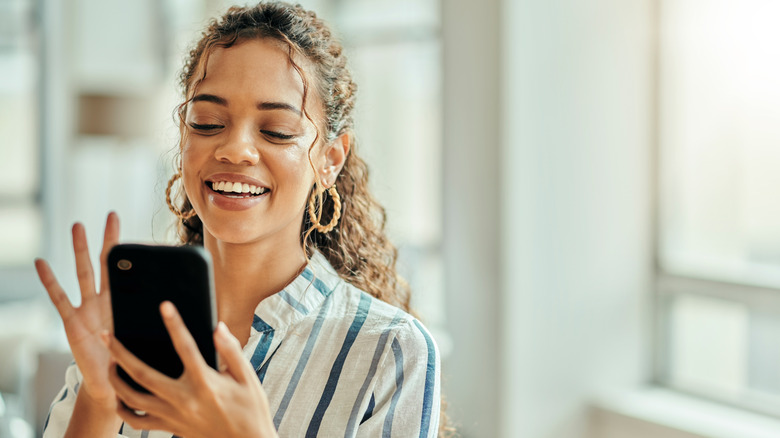 woman smiling holding smartphone