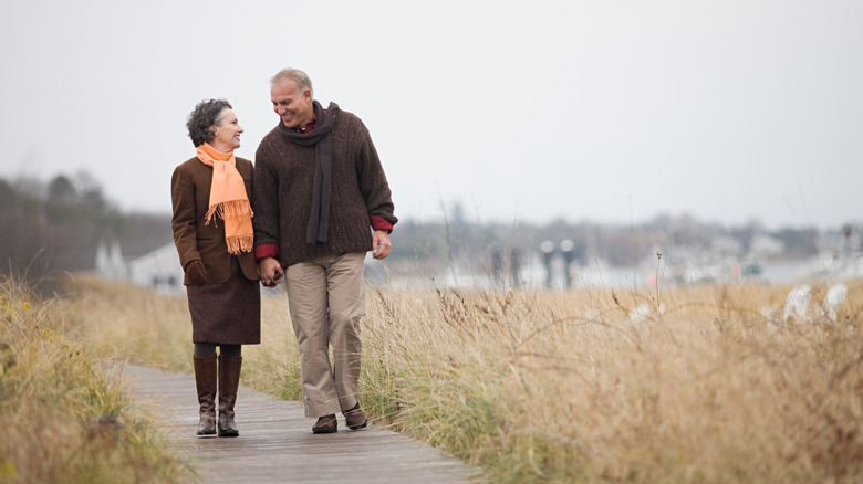 Older couple strolls on boardwalk.