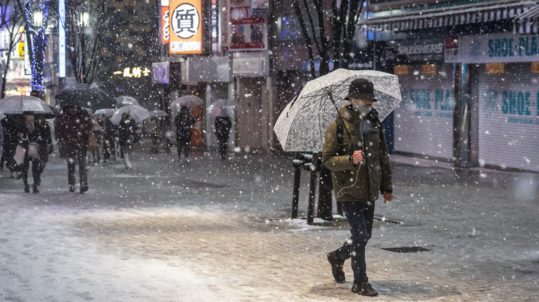 Man holding umbrella in snow.