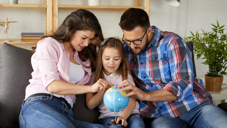 family pointing to locations on globe