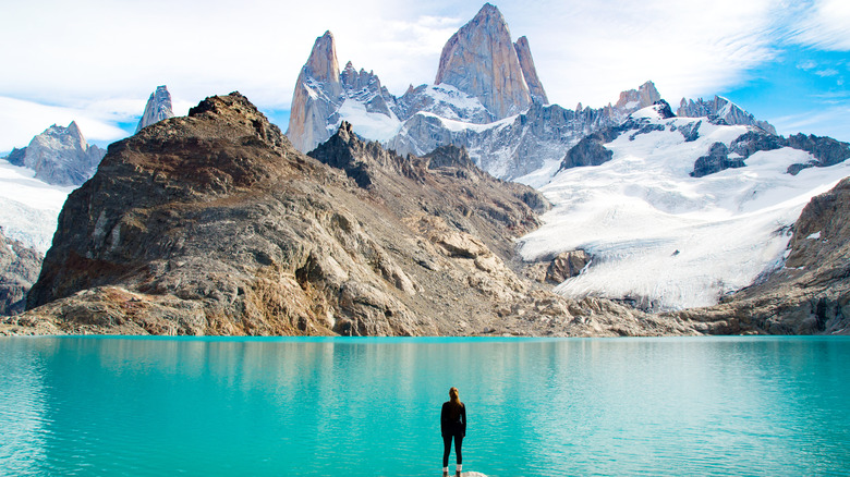 woman looking at blue lake and mountain