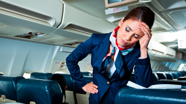 flight attendant with hand raised to her head