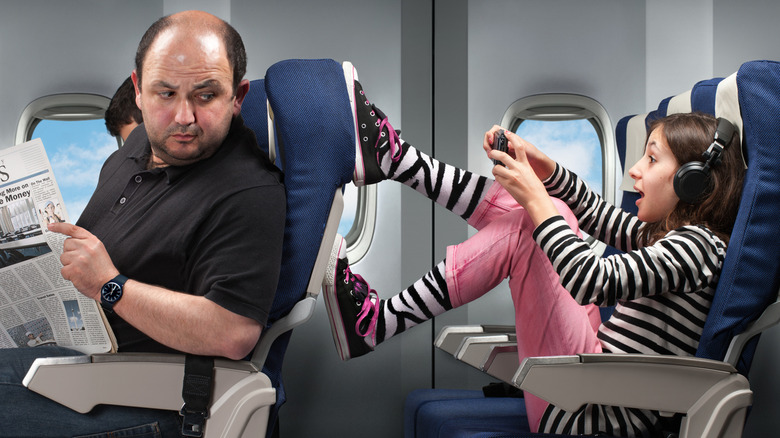 girl kicking man's seat on plane