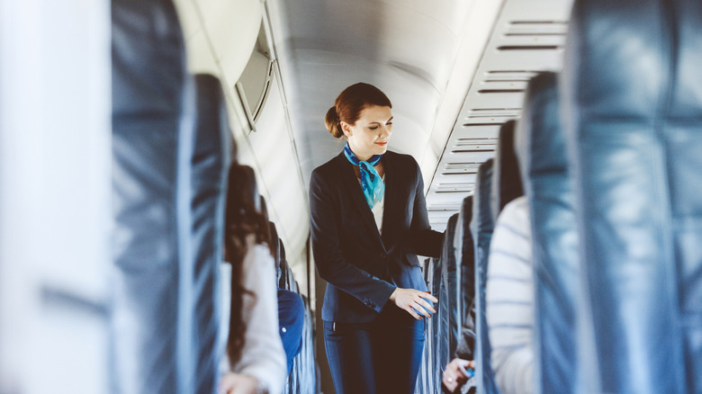 flight attendant walking down plane aisle