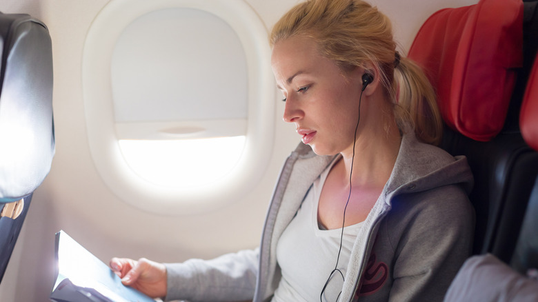 woman using earbuds on plane