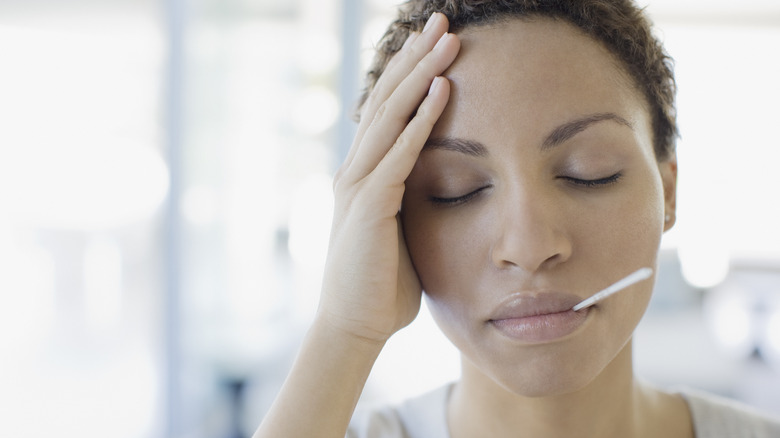 ill woman taking temperature