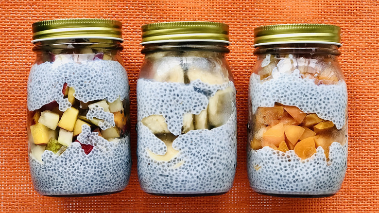 Three jars of chia pudding with apples, pears, and peaches