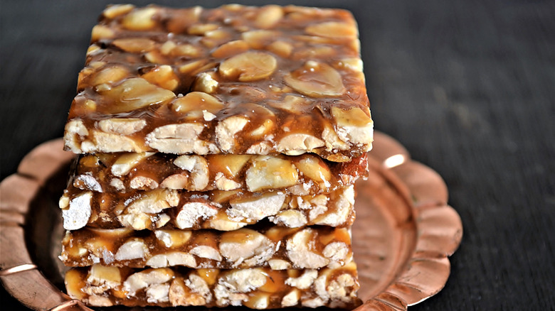 Five peanut chikki slices stacked on tray