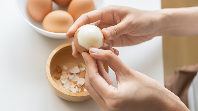 A person removing the shell from a hard boiled egg