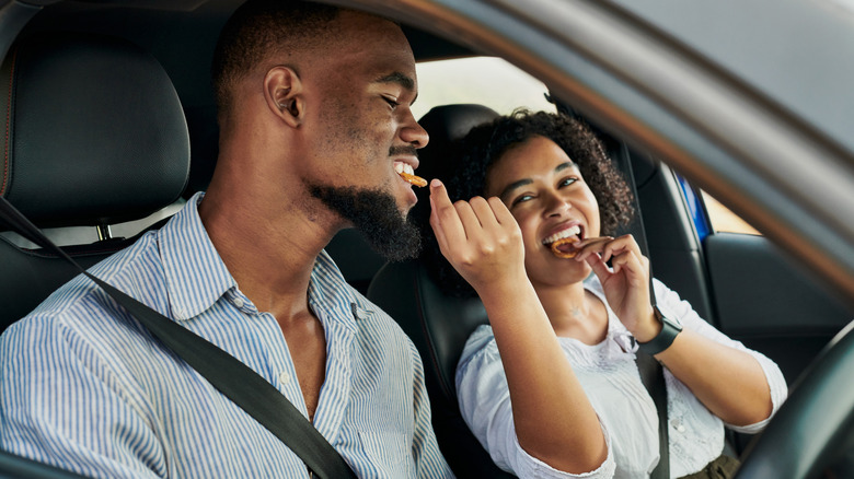 Woman feeding partner snacks while driving