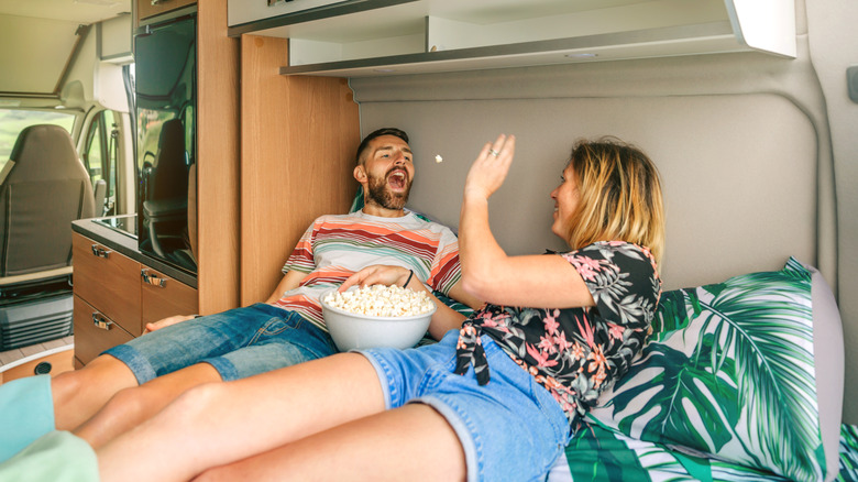 A man and woman enjoying popcorn in an RV