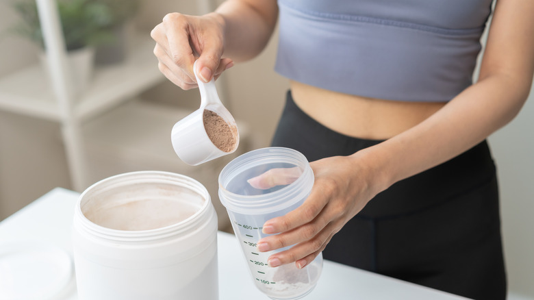 Woman adding protein powder to bottle