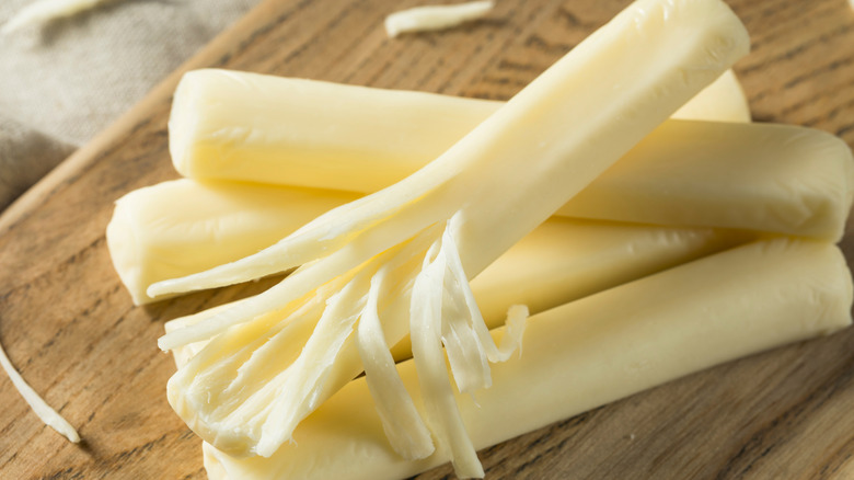 Five string cheese sticks on wooden platter