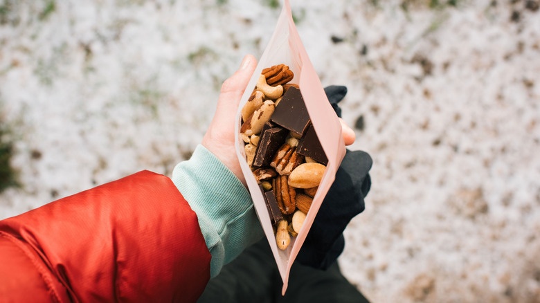 A person holding a bag of trail mix outside