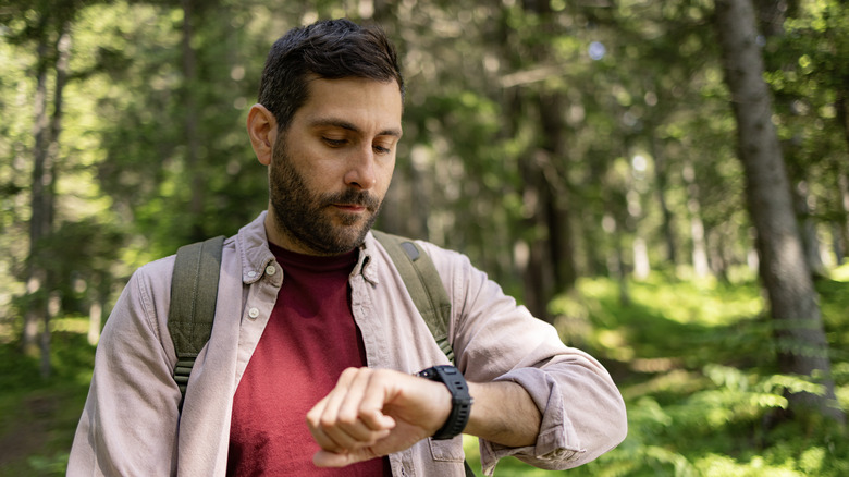 man in woods checking time