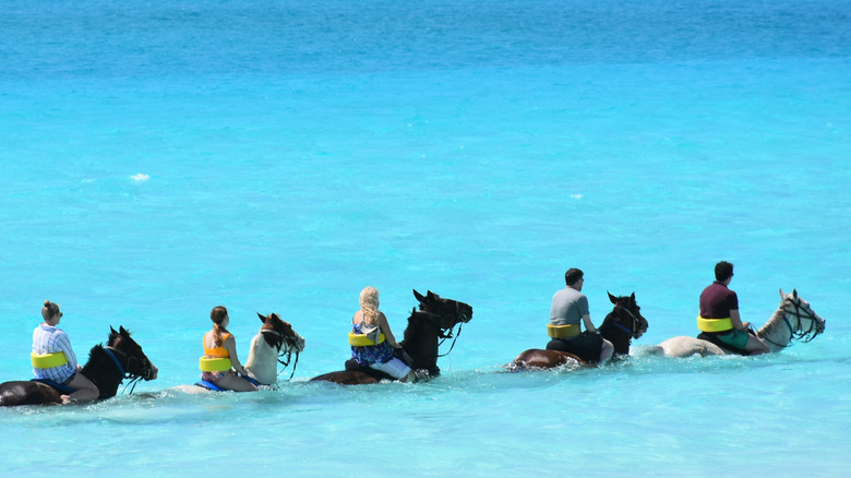people riding horses in ocean