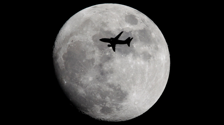 The moon with a silhouette of a plane in front of it