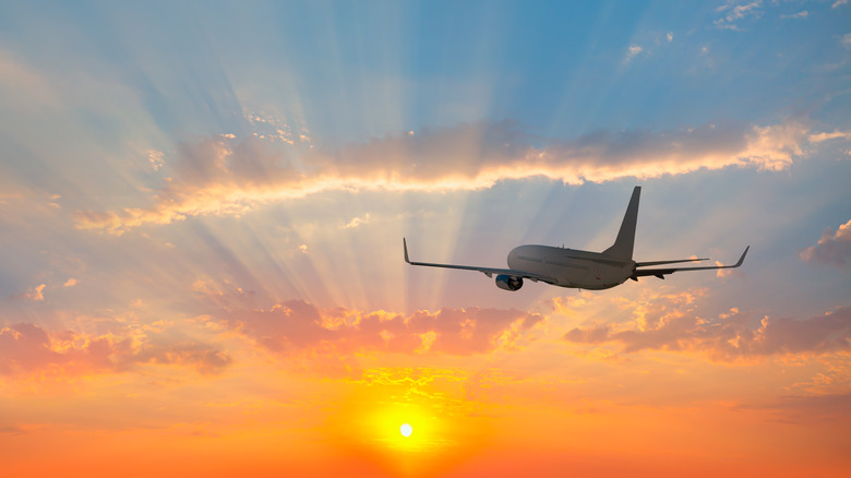 airplane flying into sunrise
