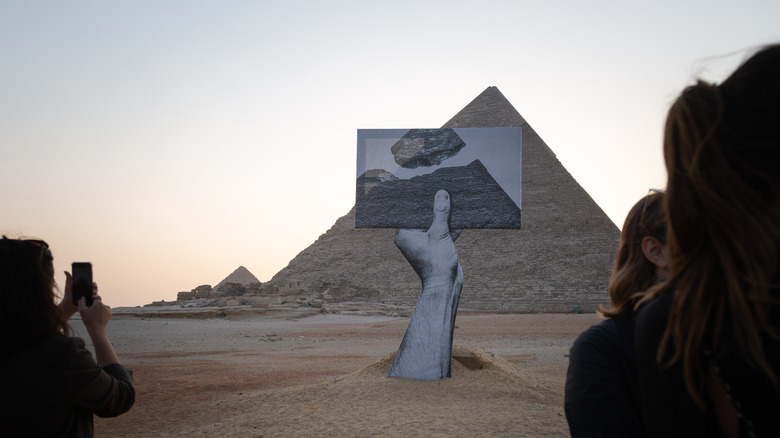 people photographing an art installation at the pyramids