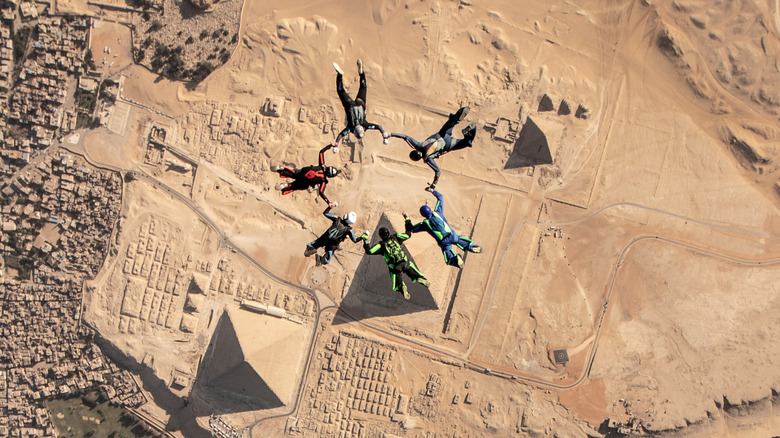 A group of six people skydiving over the pyramids