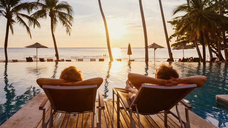 couple relaxing on tropical beach at sunset in hotel