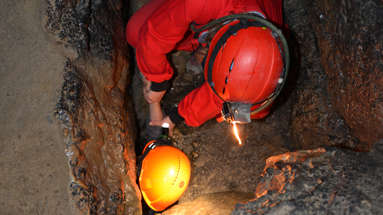 spelunkers navigating a tight squeeze