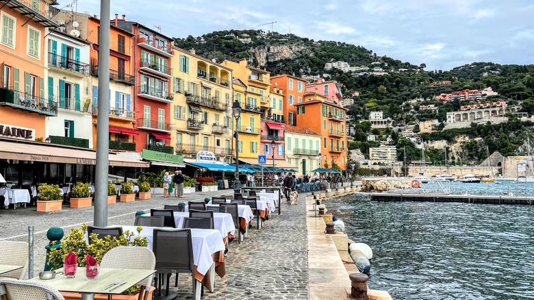 Colorful buildings and dining tables near the ocean.