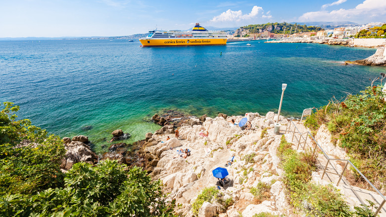 A cruise ship on the water near a rocky coastline.