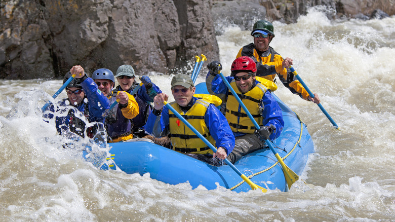 A group of men navigate intense whitwater river rapids in a raft