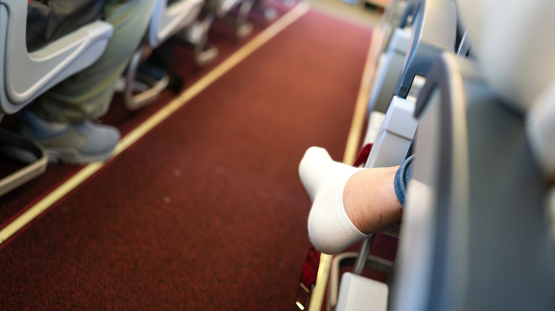 Airplane aisle with socked foot sticking out of seat