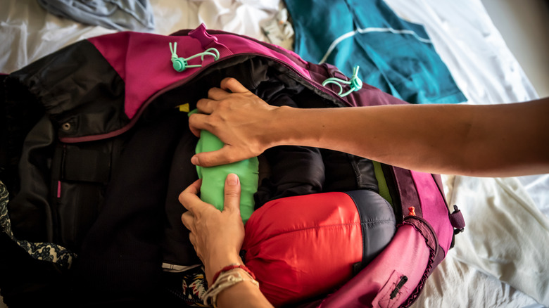 Woman packing rolled clothes into a backpack