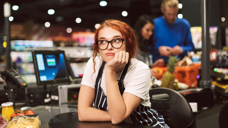 Ambivalent cashier stares into space