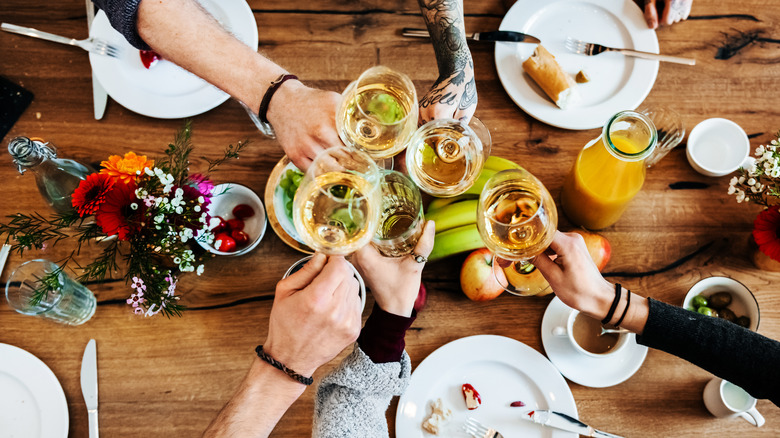 A group of people cheers with wine glasses over a table of food