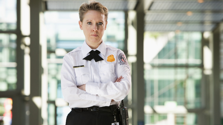 A TSA agent glares at camera with arms folded