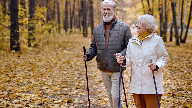 A senior couple walks with trekking poles