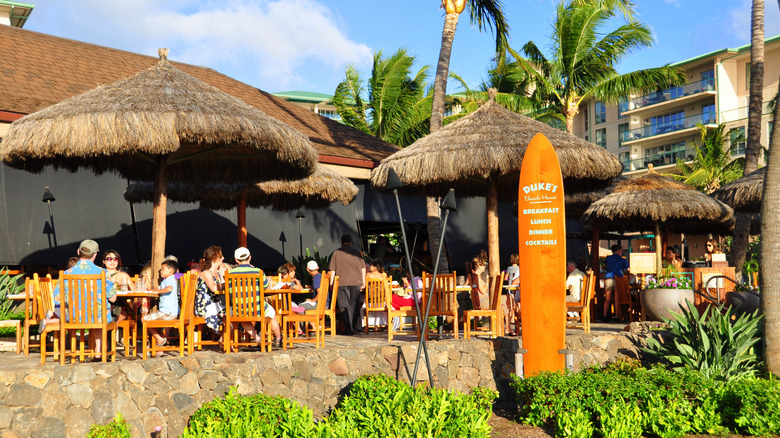 Diners under thatch umbrellas at Duke's Beach House