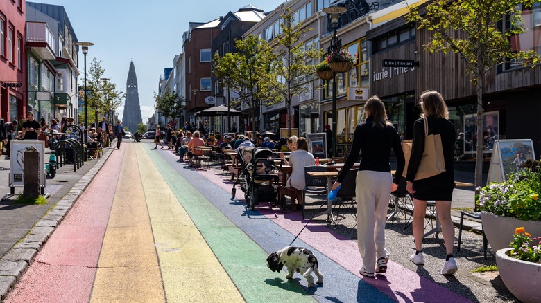 People walking dog down rainbow painted street in Reykjavik, Iceland