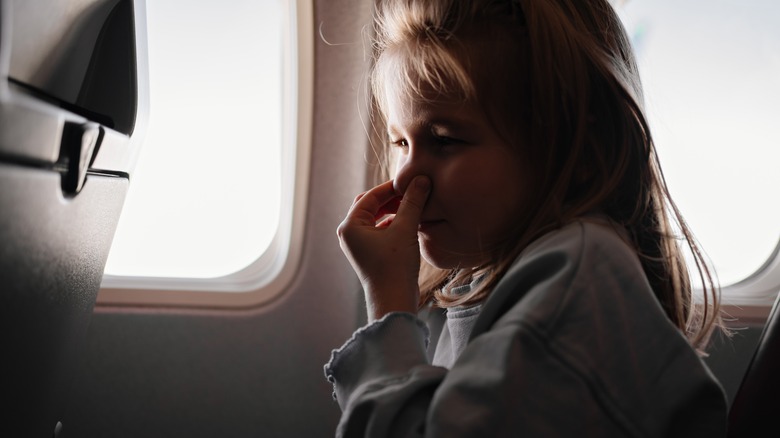 girl on flight holding nose