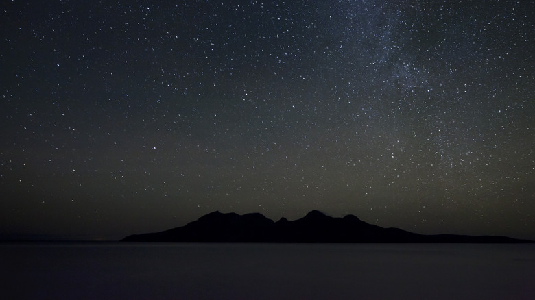 A star-filled night sky, with the edge of the Milky Way visible, over the Isle of Rum.