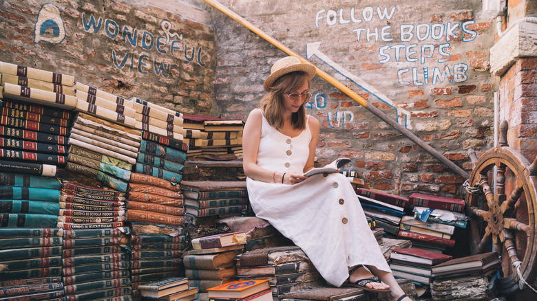 A woman perches on a pile of books at Libreria Acqua Alta