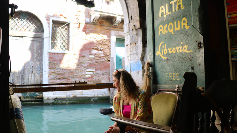 A woman sits by the canal at Libreria Acqua Alta