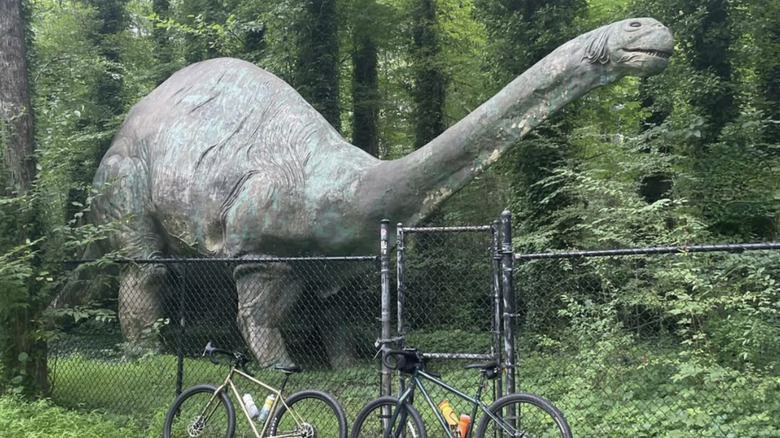 Bronto sculpture stands behind chainlink fence