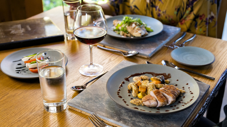 Plates of food and a glass of wine on dining room table