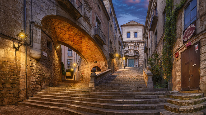 A stairway leads up to a lamplit walkway in Girona, Spain